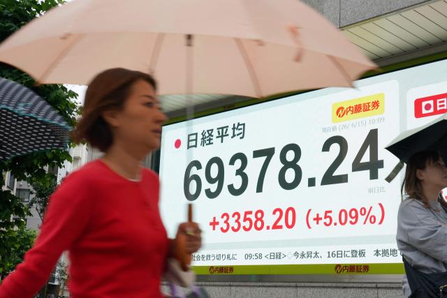Pedestrians walk past an electronic quotation board displaying the Nikkei Stock Average on the Tokyo Stock Exchange in Tokyo on June 15, 2026. (Photo by Kazuhiro NOGI / AFP)