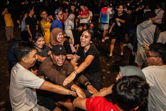 Members of the "Playing Community" group react as they play an Indonesian children's game at the Gelora Bung Karno Stadium compounds in Jakarta on May 22, 2026. Members of the group gather after work every Friday to let off steam by playing nostalgic Indonesian children's games. Similar get-togethers have sprung up elsewhere in the Southeast Asian nation as larger numbers of burnt-out workers seek novel solutions for handling stress and maintaining mental health. (Photo by Aditya Irawan / AFP) / To go with 'Indonesia-Social-Game-Psychology' Feature by Dessy SAGITA