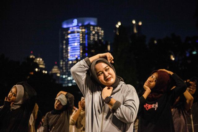 Members of the "Playing Community" group warm up before taking part in Indonesian children's games at the Gelora Bung Karno Stadium compounds in Jakarta on May 22, 2026. Members of the group gather after work every Friday to let off steam by playing nostalgic Indonesian children's games. Similar get-togethers have sprung up elsewhere in the Southeast Asian nation as larger numbers of burnt-out workers seek novel solutions for handling stress and maintaining mental health. (Photo by Aditya Irawan / AFP) / To go with 'Indonesia-Social-Game-Psychology' Feature by Dessy SAGITA