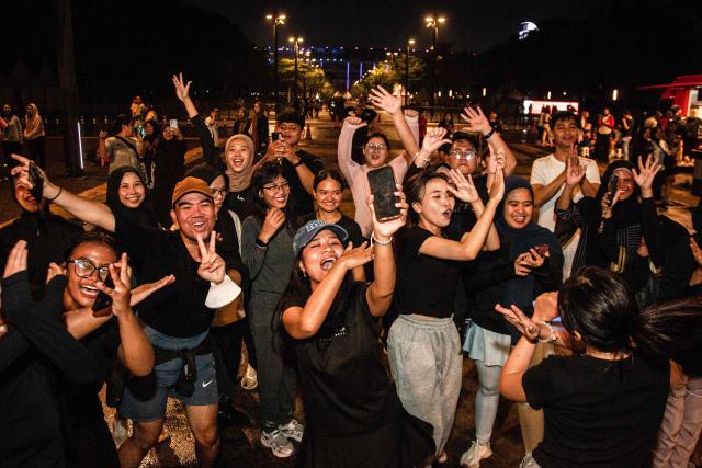 Members of the "Playing Community" take part in an Indonesian children's game at the Gelora Bung Karno Stadium compounds in Jakarta on May 22, 2026. Members of the group gather after work every Friday to let off steam by playing nostalgic Indonesian children's games. Similar get-togethers have sprung up elsewhere in the Southeast Asian nation as larger numbers of burnt-out workers seek novel solutions for handling stress and maintaining mental health. (Photo by Aditya Irawan / AFP) / To go with 'Indonesia-Social-Game-Psychology' Feature by Dessy SAGITA
