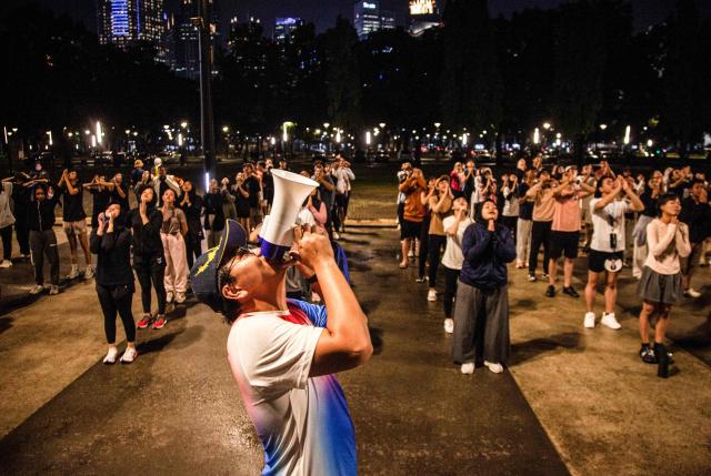 Members of the "Playing Community" group warm up before taking part in Indonesian children's games at the Gelora Bung Karno Stadium compounds in Jakarta on May 22, 2026. Members of the group gather after work every Friday to let off steam by playing nostalgic Indonesian children's games. Similar get-togethers have sprung up elsewhere in the Southeast Asian nation as larger numbers of burnt-out workers seek novel solutions for handling stress and maintaining mental health. (Photo by Aditya Irawan / AFP) / To go with 'Indonesia-Social-Game-Psychology' Feature by Dessy SAGITA
