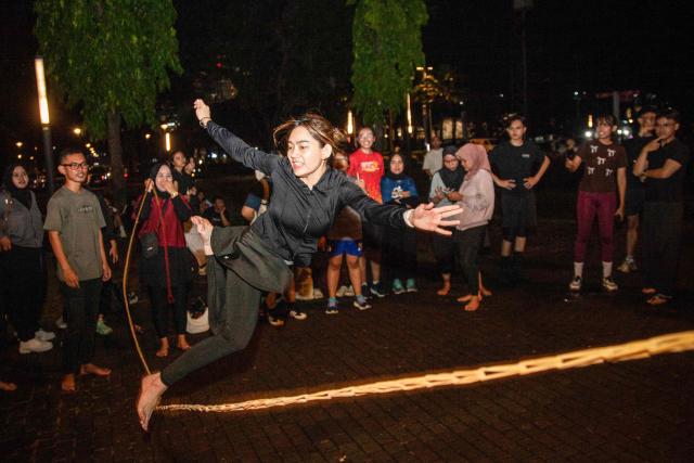 A member of the "Playing Community" group takes part in lompat tali karet (jump rope), an Indonesian children's game, at the Gelora Bung Karno Stadium compounds in Jakarta on May 22, 2026. Members of the group gather after work every Friday to let off steam by playing nostalgic Indonesian children's games. Similar get-togethers have sprung up elsewhere in the Southeast Asian nation as larger numbers of burnt-out workers seek novel solutions for handling stress and maintaining mental health. (Photo by Aditya Irawan / AFP) / To go with 'Indonesia-Social-Game-Psychology' Feature by Dessy SAGITA