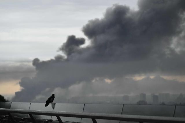 A bird is seen perched at a lookout point while smoke rises following a Russian missile strike on the Ukrainian capital Kyiv on June 15, 2026, amid the Russian invasion in Ukraine. Russia fired a barrage of missiles at several major Ukrainian cities, setting Kyiv's historic Dormition Cathedral on fire and killing nine, while Ukraine strikes claimed three lives south of Moscow. (Photo by Genya SAVILOV / AFP)