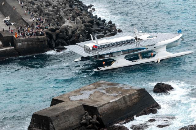 The traditional wooden canoe called Ovayan (Golden Friendship) sails alongside the support vessel 'Porrimap' after departing for its voyage to Philippines' Batanes Islands, along the coastline at Orchid island (or Lanyu island), southeastern Taiwan on June 15, 2026. (Photo by CHENG Yu-chen / AFP)