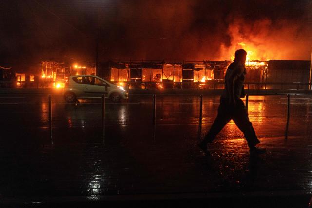 A resident walks in front of a burning market following a Russian missile strike in Kyiv on June 15, 2026, amid the Russian invasion in Ukraine. Russia fired a barrage of missiles at several major Ukrainian cities, setting Kyiv's historic Dormition Cathedral on fire and killing nine, while Ukraine strikes claimed three lives south of Moscow. (Photo by OLEKSII FILIPPOV / AFP)