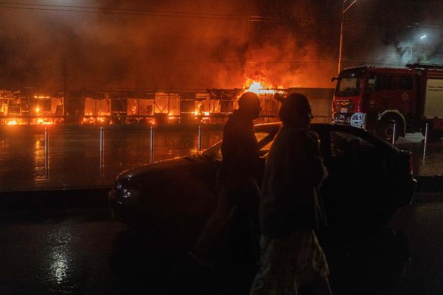 Residents walk in front of a burning market following a Russian missile strike in Kyiv on June 15, 2026, amid the Russian invasion in Ukraine. Russia fired a barrage of missiles at several major Ukrainian cities, setting Kyiv's historic Dormition Cathedral on fire and killing nine, while Ukraine strikes claimed three lives south of Moscow. (Photo by OLEKSII FILIPPOV / AFP)