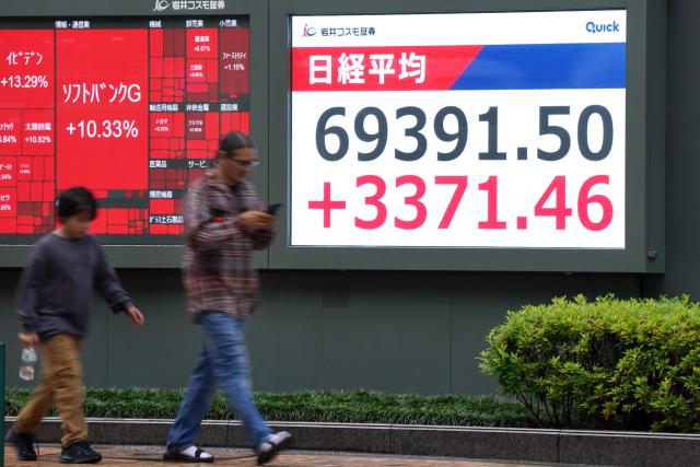 Pedestrians walk past an electronic quotation board displaying the Nikkei Stock Average on the Tokyo Stock Exchange in Tokyo on June 15, 2026. (Photo by Kazuhiro NOGI / AFP)