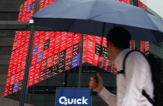 A man looks at an electronic quotation board displaying the Nikkei 225 stock prices on the Tokyo Stock Exchange in Tokyo on June 15, 2026. (Photo by Kazuhiro NOGI / AFP)