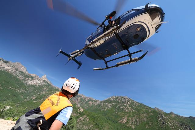 A member of Ajaccio's High Mountain Gendarmerie Platoon (PGHM, Peleton de Gendarmerie de Haute Montagne), an elite unit of the French Gendarmerie specializing in mountain rescue and law enforcement in high-altitude and alpine environments, looks at the gendarmes helicopter during the rescue of an injuried tourist inside the Bavella mountain in Zonza on the French Mediterranean island of Corsica on June 12, 2026. (Photo by Pascal POCHARD-CASABIANCA / AFP)