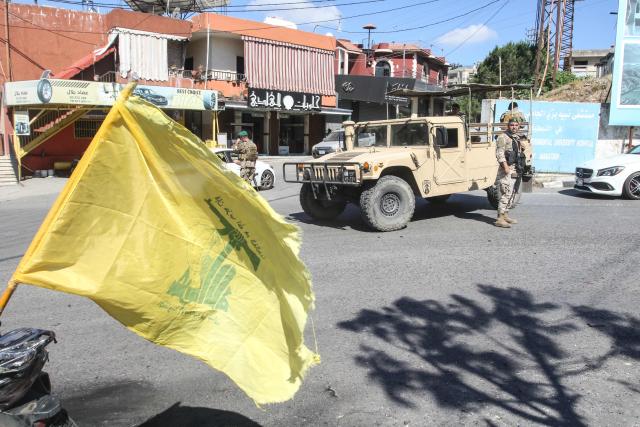 Lebanese soldiers man a checkpoint beside a Hezbollah flag at the entrance to Nabatieh on June 15, 2026. The United States and Iran said they reached a deal to end the Middle East war on all fronts including Lebanon, and reopen the vital Strait of Hormuz, but offered little indication on the thorny question of Tehran's nuclear programme. Washington and Islamabad said the agreement was to be signed on June 19 in Switzerland, signalling what would be a major breakthrough to ending months of war that have taken thousands of lives and roiled energy markets. (Photo by Mahmoud ZAYYAT / AFP) / 