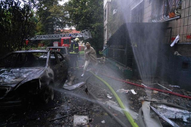 A resident walks among debris as firefighters work to extinguish a fire in a residential building, which was hit during a Russian missile and drone strike on the Ukrainian capital Kyiv on June 15, 2026, amid the Russian invasion of Ukraine. Russia fired a barrage of missiles at several major Ukrainian cities, setting fire to Kyiv's historic Dormition Cathedral at the UNESCO world heritage site Kyiv-Pechersk Lavra and killing eleven, while Ukraine strikes claimed three lives in a city south of Moscow. (Photo by OLEKSII FILIPPOV / AFP)