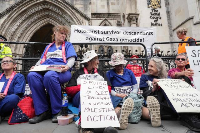 Protesters hold placards as they sit outside the Royal Courts Of Justice in central London on June 15, 2026, as the High Court rules on a legal standoff between the government and activist group Palestine Action. Britain's Prime Minister Keir Starmer's Labour government banned Palestine Action as a terrorist organisation in 2025, making it a criminal offence to belong to or support the group. (Photo by CARLOS JASSO / AFP)