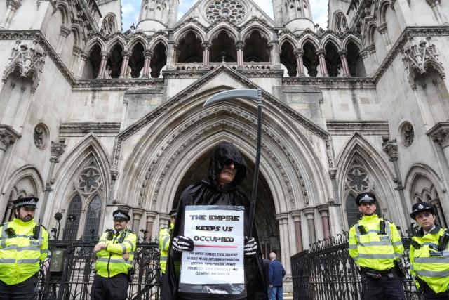 A protester dressed as the Grim Reaper holds a placard outside the Royal Courts Of Justice in central London on June 15, 2026, as the High Court rules on a legal standoff between the government and activist group Palestine Action. Britain's Prime Minister Keir Starmer's Labour government banned Palestine Action as a terrorist organisation in 2025, making it a criminal offence to belong to or support the group. (Photo by CARLOS JASSO / AFP)