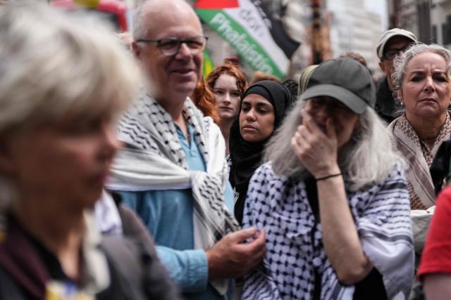 People stand listening to the court proceedings outside the Royal Courts Of Justice in central London on June 15, 2026, as the High Court rules on a legal standoff between the government and activist group Palestine Action. Britain's Prime Minister Keir Starmer's Labour government banned Palestine Action as a terrorist organisation in 2025, making it a criminal offence to belong to or support the group. (Photo by CARLOS JASSO / AFP)