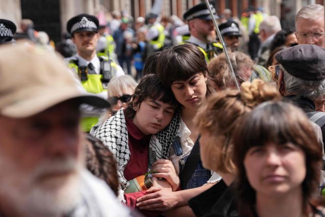 People stand listening to the court proceedings outside the Royal Courts Of Justice in central London on June 15, 2026, as the High Court rules on a legal standoff between the government and activist group Palestine Action. Britain's Prime Minister Keir Starmer's Labour government banned Palestine Action as a terrorist organisation in 2025, making it a criminal offence to belong to or support the group. (Photo by CARLOS JASSO / AFP)