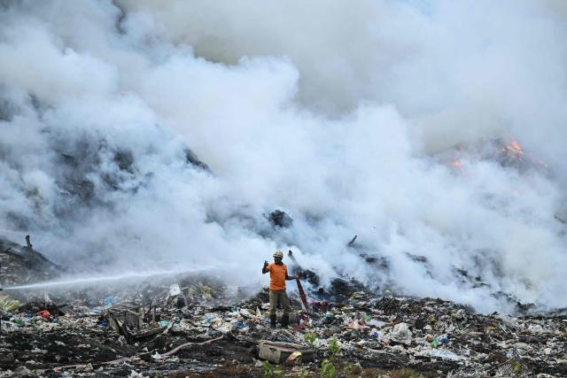 A firefighter tries to extinguish burning garbage after a fire broke out at the Perungudi waste dumpyard in Chennai on June 15, 2026. (Photo by R. Satish BABU / AFP)