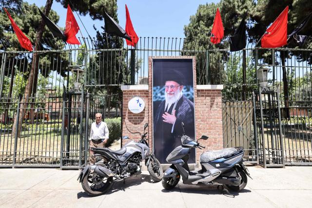 A man walks past a portrait of slain Iranian supreme leader Ayatollah Ali Khamenei as he leaves the former US embassy in Tehran on June 15, 2026. The United States and Iran agreed a peace deal and an "immediate and permanent" end to military operations on all fronts including Lebanon, mediator Pakistan said, signaling the apparent end to more than three months of war in Middle East. (Photo by ATTA KENARE / AFP) / 