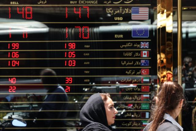 Women walk past a currency exchange office in Tehran on June 15, 2026. The United States and Iran agreed a peace deal and an "immediate and permanent" end to military operations on all fronts including Lebanon, mediator Pakistan said, signaling the apparent end to more than three months of war in Middle East. (Photo by ATTA KENARE / AFP) / 