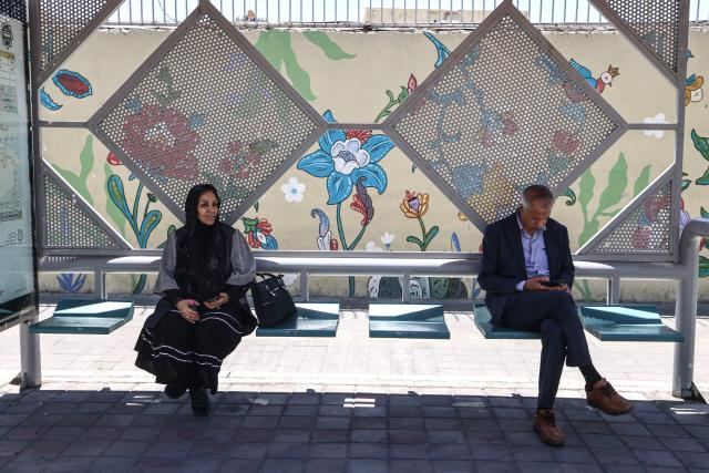 Iranians sit at a bus stop in Tehran on June 15, 2026. The United States and Iran agreed a peace deal and an "immediate and permanent" end to military operations on all fronts including Lebanon, mediator Pakistan said, signaling the apparent end to more than three months of war in Middle East. (Photo by ATTA KENARE / AFP) / 