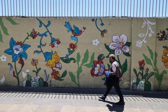 An Iranian man walks past a mural in Tehran on June 15, 2026. The United States and Iran agreed a peace deal and an "immediate and permanent" end to military operations on all fronts including Lebanon, mediator Pakistan said, signaling the apparent end to more than three months of war in Middle East. (Photo by ATTA KENARE / AFP) / 