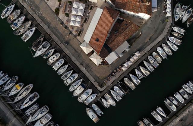 This aerial photograph shows boats moored at a marina surrounding a little island in Saint-Martin-de-Ré, on the northern shore of the Ré island along the Atlantic Ocean, southwestern France on June 13, 2026. The marina consists in a circular tidal basin protected by a lock and shelters up to 280 boats. (Photo by Christophe ARCHAMBAULT / AFP)