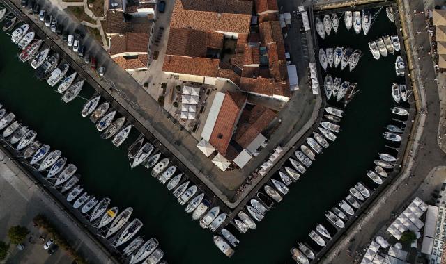 This aerial photograph shows boats moored at a marina surrounding a little island in Saint-Martin-de-Ré, on the northern shore of the Ré island along the Atlantic Ocean, southwestern France on June 13, 2026. The marina consists in a circular tidal basin protected by a lock and shelters up to 280 boats. (Photo by Christophe ARCHAMBAULT / AFP)