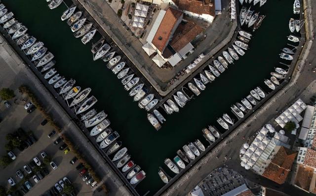 This aerial photograph shows boats moored at a marina surrounding a little island in Saint-Martin-de-Ré, on the northern shore of the Ré island along the Atlantic Ocean, southwestern France on June 13, 2026. The marina consists in a circular tidal basin protected by a lock and shelters up to 280 boats. (Photo by Christophe ARCHAMBAULT / AFP)