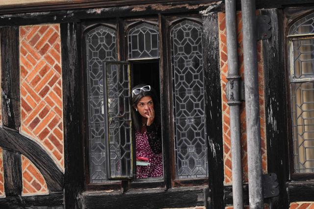 A woman watches from a window of the castle during the annual Order of the Garter service at St. George's Chapel in Windsor Castle, west of London, on June 15, 2026. The Order of the Garter is the oldest and most senior Order of Chivalry in Britain, established by King Edward III nearly 700 years ago. (Photo by Jordan Pettitt / POOL / AFP)