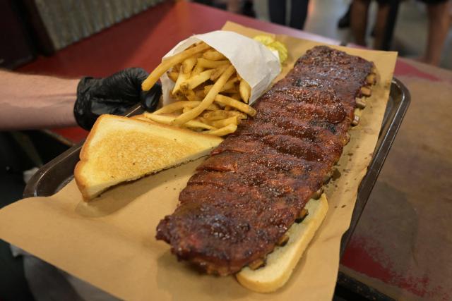 A staff members serves and order of ribs at Joe's Kansas City  BAR-B-QUE barbecue restaurant in Kansas City, Missouri, United States on June 14, 2026, ahead of the 2026 World Cup football match between Argentina and Algeria. (Photo by JUAN MABROMATA / AFP)