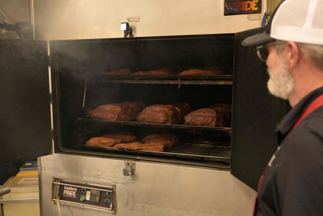A cook stand beside a smoker with ribs and briskets at Joe's Kansas City  BAR-B-QUE barbecue restaurant in Kansas City, Missouri, United States on June 14, 2026, ahead of the 2026 World Cup football match between Argentina and Algeria. (Photo by JUAN MABROMATA / AFP)