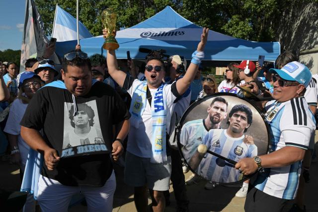 Argentina supporters gather around a drum depicting Lionel Messi and Diego Maradona as they take part in a "banderazo" flag-waving gathering outside "Los Hornos" restaurant that caters Argentinian barbecue specialties, near Kansas City, Missouri, United States on June 14, 2026, ahead of the 2026 World Cup football match between Argentina and Algeria. (Photo by JUAN MABROMATA / AFP)