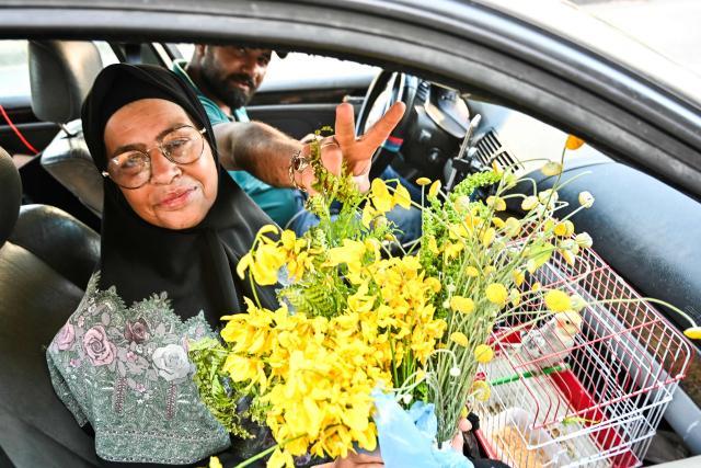 Holding a bunch of flowers and a caged bird, displaced people drive along the highway of the coastal city of Sidon as they return to their home villages in southern Lebanon on June 15, 2026. Israel's defence minister said on June 15 that Israeli forces would remain in Lebanon, Syria and Gaza indefinitely, hours after the United States and Iran agreed to end the Middle East war, including in Lebanon.  Lebanon was drawn into the Middle East war on March 2 when Tehran-backed militant group Hezbollah launched attacks on Israel to avenge the killing of the Iranian leader. Israel has responded with broad strikes across Lebanon and a ground offensive. (Photo by FADEL itani / AFP) / 