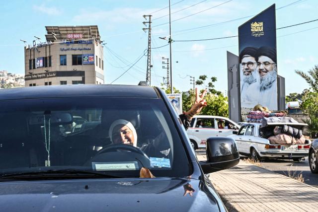 A woman flashes the V-sign as she drives along the highway through the area of of the coastal town of Ghazieyh as families return to their home villages in southern Lebanon on June 15, 2026. Israel's defence minister said on June 15 that Israeli forces would remain in Lebanon, Syria and Gaza indefinitely, hours after the United States and Iran agreed to end the Middle East war, including in Lebanon.  Lebanon was drawn into the Middle East war on March 2 when Tehran-backed militant group Hezbollah launched attacks on Israel to avenge the killing of the Iranian leader. Israel has responded with broad strikes across Lebanon and a ground offensive. (Photo by FADEL itani / AFP) / 