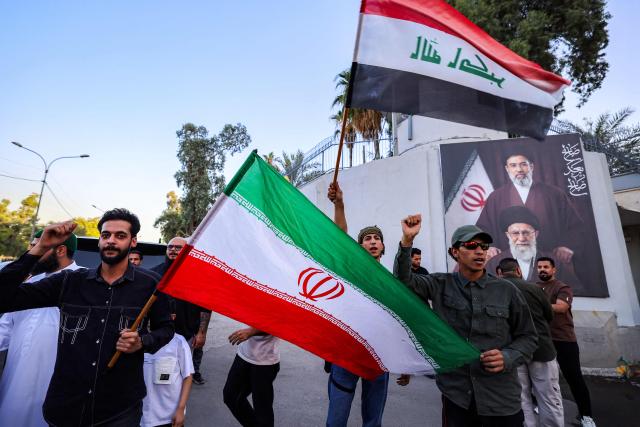 People gather waving flags of Iran and Iraq outside the Iranian embassy headquarters in Baghdad on June 15, 2026, during celebrations following the announcement of a deal to end the war between Iran and the US. The US president said on June 15 that the Strait of Hormuz would be fully open later in the week, after Washington and Tehran announced a deal to end the Middle East war. Iran had blockaded the vital waterway since the start of the conflict after US-Israeli strikes on the Islamic republic in late February. (Photo by AHMAD AL-RUBAYE / AFP) / 