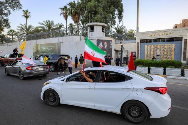 People ride in vehicles waving flags of Iraq, Iran, Lebanon and Hezbollah past the Iranian embassy headquarters in Baghdad on June 15, 2026, during celebrations following the announcement of a deal to end the war between Iran and the US. The US president said on June 15 that the Strait of Hormuz would be fully open later in the week, after Washington and Tehran announced a deal to end the Middle East war. Iran had blockaded the vital waterway since the start of the conflict after US-Israeli strikes on the Islamic republic in late February. (Photo by AHMAD AL-RUBAYE / AFP) / 