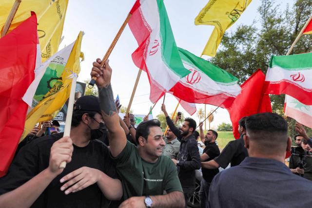 People gather waving flags of Iran, Lebanon, and others near the Iranian embassy headquarters in Baghdad on June 15, 2026, during celebrations following the announcement of a deal to end the war between Iran and the US. The US president said on June 15 that the Strait of Hormuz would be fully open later in the week, after Washington and Tehran announced a deal to end the Middle East war. Iran had blockaded the vital waterway since the start of the conflict after US-Israeli strikes on the Islamic republic in late February. (Photo by AHMAD AL-RUBAYE / AFP) / 