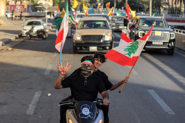 Youths ride scooters and vehicles while waving flags of Iraq, Iran, Lebanon and Hezbollah in Baghdad on June 15, 2026, during celebrations following the announcement of a deal to end the war between Iran and the US. The US president said on June 15 that the Strait of Hormuz would be fully open later in the week, after Washington and Tehran announced a deal to end the Middle East war. Iran had blockaded the vital waterway since the start of the conflict after US-Israeli strikes on the Islamic republic in late February. (Photo by AHMAD AL-RUBAYE / AFP) / 