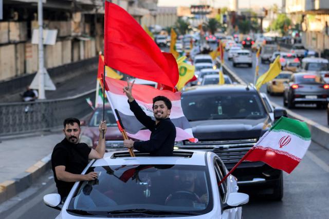 Youths ride vehicles while waving flags of Iraq, Iran, Lebanon and Hezbollah in Baghdad on June 15, 2026, during celebrations following the announcement of a deal to end the war between Iran and the US. The US president said on June 15 that the Strait of Hormuz would be fully open later in the week, after Washington and Tehran announced a deal to end the Middle East war. Iran had blockaded the vital waterway since the start of the conflict after US-Israeli strikes on the Islamic republic in late February. (Photo by AHMAD AL-RUBAYE / AFP) / 