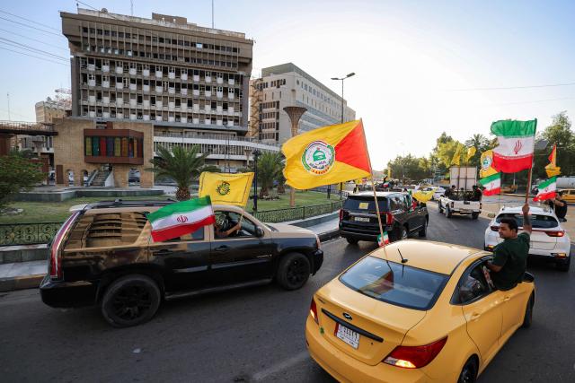 Youths ride vehicles while waving flags of Iraq and others in Baghdad on June 15, 2026, during celebrations following the announcement of a deal to end the war between Iran and the US. The US president said on June 15 that the Strait of Hormuz would be fully open later in the week, after Washington and Tehran announced a deal to end the Middle East war. Iran had blockaded the vital waterway since the start of the conflict after US-Israeli strikes on the Islamic republic in late February. (Photo by AHMAD AL-RUBAYE / AFP) / 