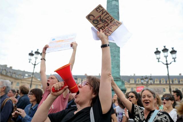 A protestor holds a slogan reading "Hear our anger" during a gathering to demand a law against violence on minors, outside the French Justice Ministry, in Place Vendome, in Paris on June 15, 2026. (Photo by Thomas SAMSON / AFP)