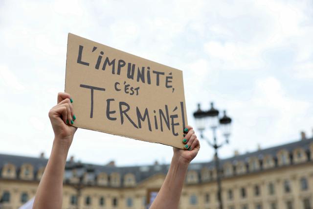 A protestor holds a slogan reading "Impunity has ended" during a gathering to demand a law against violence on minors, outside the French Justice Ministry, in Place Vendome, in Paris on June 15, 2026. (Photo by Thomas SAMSON / AFP)