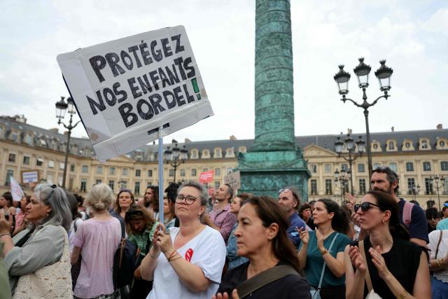 A protestor holds a slogan reading "Protect our children, damn it!" during a gathering to demand a law against violence on minors, outside the French Justice Ministry, in Place Vendome, in Paris on June 15, 2026. (Photo by Thomas SAMSON / AFP)