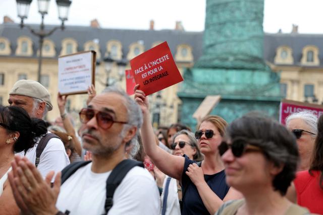 A protestor holds a slogan reading "Face à l'inceste (association) supports the comprehensive law" during a gathering to demand a law against violence on minors, outside the French Justice Ministry, in Place Vendome, in Paris on June 15, 2026. (Photo by Thomas SAMSON / AFP)