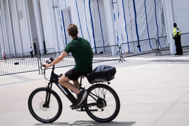 A cyclist looks at a tarp covering signage along the facade of the Kennedy Center in Washington, DC, on June 15, 2026, after a judge ordered the removal of US President Donald Trump's name from the building. Workers removed President Donald Trump's name from the facade of the prestigious Kennedy Center in Washington on June 13 -- a stinging defeat for the US leader who has eschewed political tradition to affix his name and likeness across public spaces. (Photo by Brendan Smialowski / AFP)