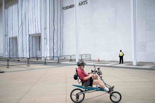 A guard stands near a tarp covering signage along the facade of the Kennedy Center in Washington, DC, on June 15, 2026, after a judge ordered the removal of US President Donald Trump's name from the building. Workers removed President Donald Trump's name from the facade of the prestigious Kennedy Center in Washington on June 13 -- a stinging defeat for the US leader who has eschewed political tradition to affix his name and likeness across public spaces. (Photo by Brendan Smialowski / AFP)