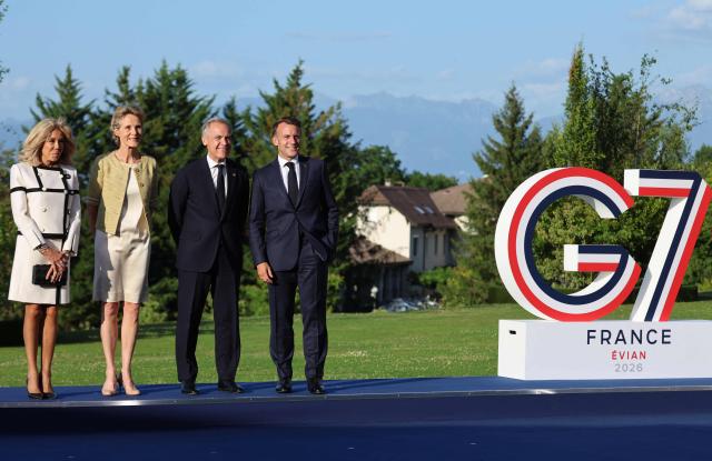 France's President Emmanuel Macron (R) and his wife Brigitte Macron (L) pose with Canada's Prime Minister Mark Carney (C-R) and his wife Diana Fox Carney during the official greeting as part of the G7 summit, in Evian, eastern France, on June 15, 2026. A G7 summit is set to take place June 15 to 17 in the French town of Evian-les-Bains near Switzerland and it will be attended by country leaders as well as the EU's foreign policy chief and ministers from Brazil, Canada, the United Arab Emirates and Turkey. (Photo by Ludovic MARIN / AFP)