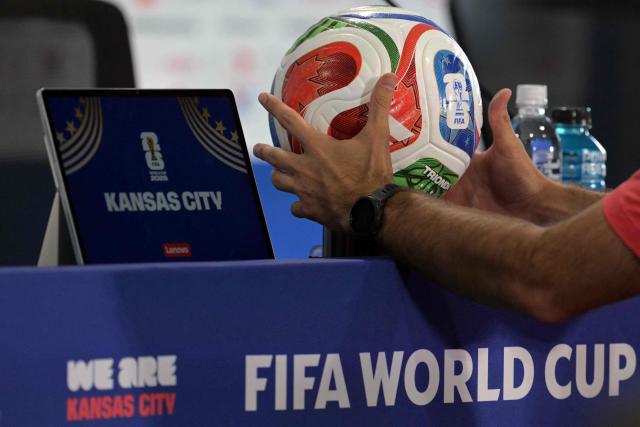 A staff member places the official match ball of the 2026 World Cup football tournament on the podium ahead of an MD-1 press conference at the Kansas City Stadium in Kansas City on June 15, 2026, on the eve of the 2026 World Cup Group J football match between Argentina and Algeria.  (Photo by JUAN MABROMATA / AFP)