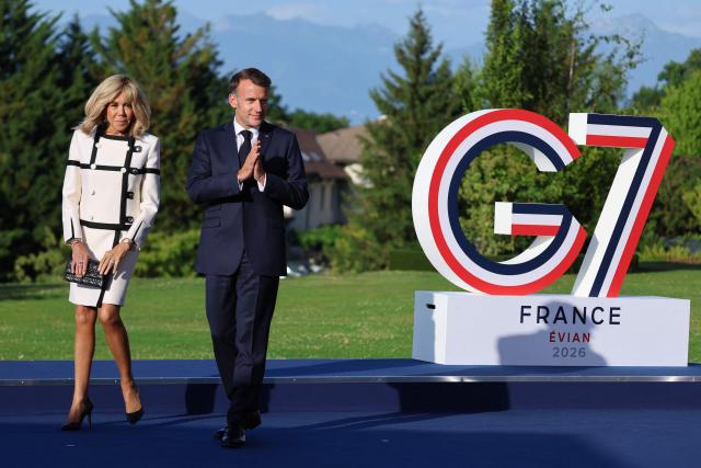 France's President Emmanuel Macron (R) gestures next to his wife Brigitte Macron during the official greeting as part of the G7 summit, in Evian, eastern France, on June 15, 2026. A G7 summit is set to take place June 15 to 17 in the French town of Evian-les-Bains near Switzerland and it will be attended by country leaders as well as the EU's foreign policy chief and ministers from Brazil, Canada, the United Arab Emirates and Turkey. (Photo by Ludovic MARIN / POOL / AFP)
