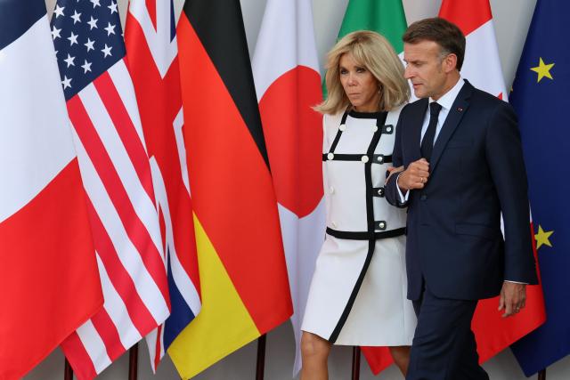 France's President Emmanuel Macron (R) and his wife Brigitte Macron arrive for the official greeting during the G7 summit, in Evian, eastern France, on June 15, 2026. A G7 summit is set to take place June 15 to 17 in the French town of Evian-les-Bains near Switzerland and it will be attended by country leaders as well as the EU's foreign policy chief and ministers from Brazil, Canada, the United Arab Emirates and Turkey. (Photo by Ludovic MARIN / AFP)