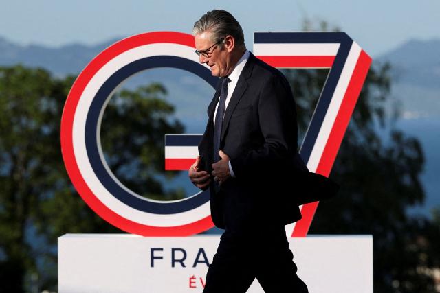 Britain's Prime Minister Keir Starmer walks past the G7 logo during the official greeting as part of the G7 summit, in Evian, eastern France, on June 15, 2026. A G7 summit is set to take place June 15 to 17 in the French town of Evian-les-Bains near Switzerland and it will be attended by country leaders as well as the EU's foreign policy chief and ministers from Brazil, Canada, the United Arab Emirates and Turkey. (Photo by Isabel Infantes / POOL / AFP)